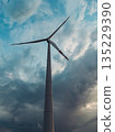 Bottom view of a tall wind turbine silhouette against dramatic sunset sky. 135229390