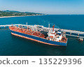Aerial view of a large oil tanker docked at a pier in the port in process of loading. 135229396