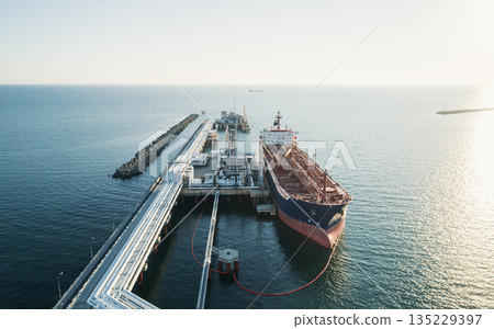 Aerial view of a large oil tanker docked at a pier in the port in process of loading. 135229397
