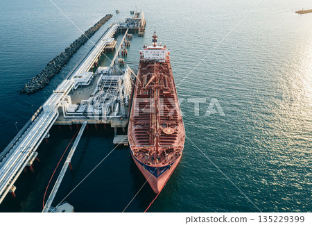 Aerial view of a large oil tanker docked at a pier in the port in process of loading. Aerial view of a large oil tanker docked at a pier in the port in process of loading. 135229399