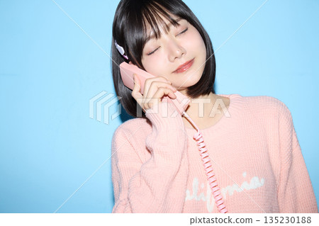 一位年輕亞洲女性在藍色背景前擺出可愛姿勢的肖像照 135230188