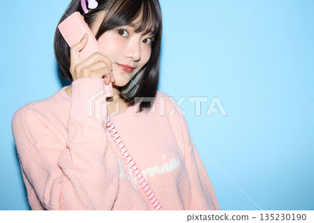 一位年輕亞洲女性在藍色背景前擺出可愛姿勢的肖像照 135230190