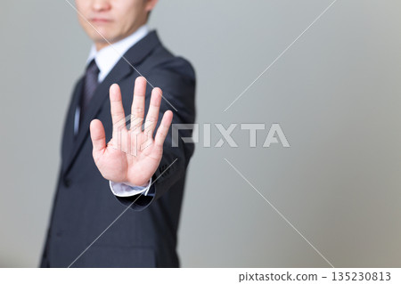 一位身穿西裝的中年男性商人擺出停止姿勢 一位身穿西裝的中年男性商人擺出停止姿勢 135230813