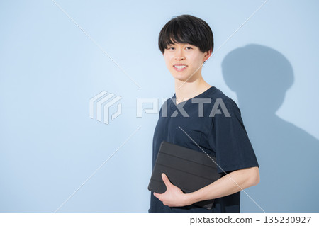 Image of a young male nurse or doctor wearing a scrub against a light blue background 135230927