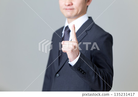 A middle-aged male businessman in a suit pointing his index finger 135231417