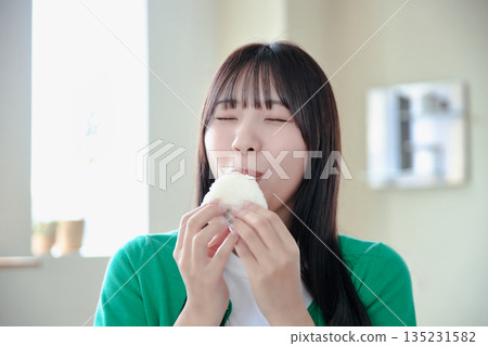 A young woman eating rice balls with relish A young woman eating rice balls with relish 135231582