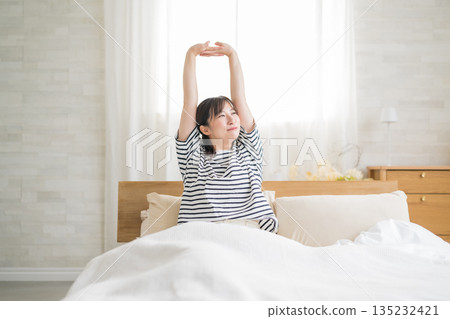 一個女人在床上伸展 一個女人在床上伸展 135232421