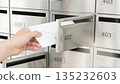 Hand checking and retrieving mail from metal mailbox. 135232603