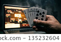 Hand holding Royal Flush cards playing online poker on laptop. 135232604