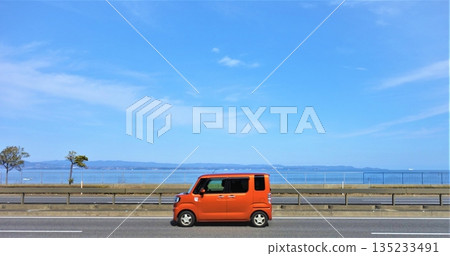 Orange car driving on Seaside Road (side view) 135233491