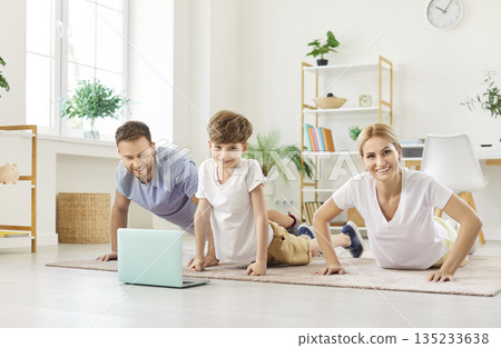 Sporty family distant sport training, parents and son watching yoga, fitness pilates video class  135233638
