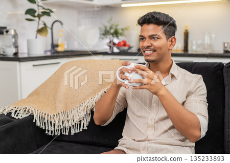 Indian man drinks hot tea holds mug takes calm sip relax mind enjoys morning before work start fresh Indian man drinks hot tea holds mug takes calm sip relax mind enjoys morning before work start fresh 135233893
