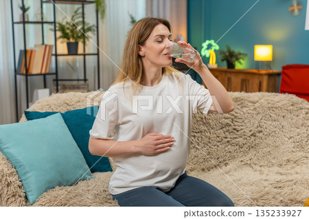 Pregnant woman drinks water gulp hand on belly shows hydration importance for pregnancy health daily Pregnant woman drinks water gulp hand on belly shows hydration importance for pregnancy health daily 135233927