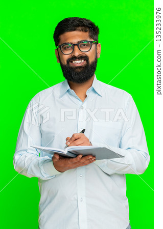 Indian man writing in notebook focused face planning daily tasks to-do list concentration gesture Indian man writing in notebook focused face planning daily tasks to-do list concentration gesture 135233976