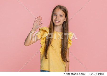 Child girl kid happily waving and smiling hello in playful mood, greeting someone in front of camera 135233981