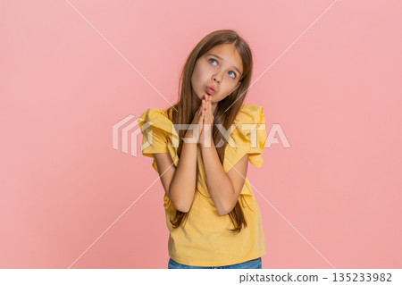 Child girl kid folds hands in prayer and looks upward as if wishing or asking for help or support Child girl kid folds hands in prayer and looks upward as if wishing or asking for help or support 135233982