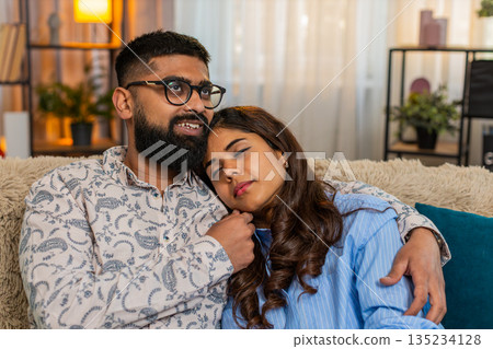 Indian couple man woman sleeping at home, girl resting on shoulder while boy touches hair gently Indian couple man woman sleeping at home, girl resting on shoulder while boy touches hair gently 135234128