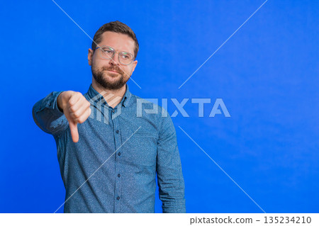 Upset man guy showing thumbs down gesture disapproval dissatisfied dislike negative feedback Upset man guy showing thumbs down gesture disapproval dissatisfied dislike negative feedback 135234210
