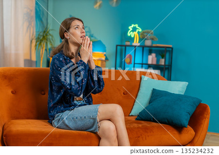 Tensed stressed woman sits at home folding palms together pray ask for help thinks begging apology 135234232