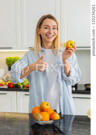 Young woman eating fresh apple in home kitchen enjoying healthy vitamins and nutrition fit lifestyle Young woman eating fresh apple in home kitchen enjoying healthy vitamins and nutrition fit lifestyle 135234261