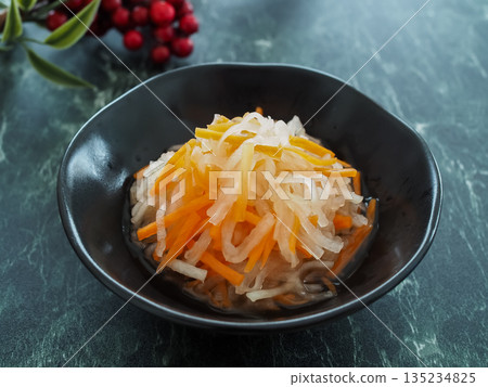 黑色盤子裡盛著紅白相間的醃菜。 135234825