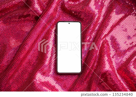 Smartphone with blank screen on sparkly red sequin fabric. 135234840