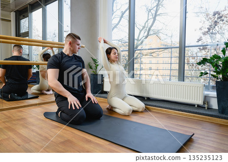 Personal trainer guiding woman during stretching exercise Personal trainer guiding woman during stretching exercise 135235123