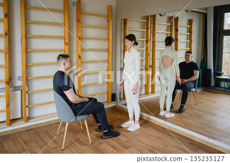 Trainer assisting man with nail standing practice indoors Trainer assisting man with nail standing practice indoors 135235127