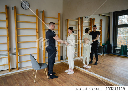 Trainer assisting man with nail standing practice indoors Trainer assisting man with nail standing practice indoors 135235129