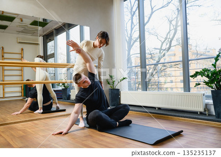 Personal trainer assisting man with stretching exercise Personal trainer assisting man with stretching exercise 135235137
