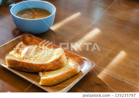 在清晨的陽光下，享用著法式吐司和湯的早餐。 135235797