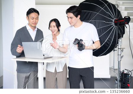 工作室裡，一男一女正在用筆記型電腦查看照片。 135236660