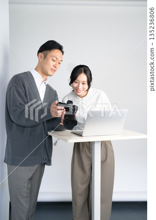 在攝影棚裡,男男女女正在電腦上查看照片。 在攝影棚裡,男男女女正在電腦上查看照片。 135236806