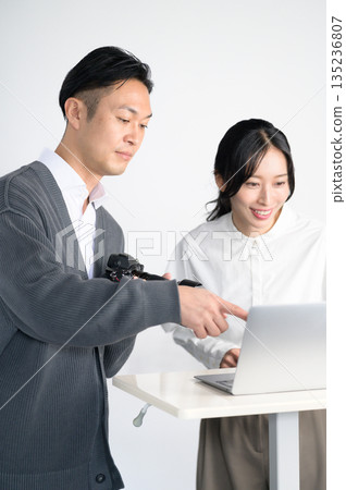 Men and women checking photos on a computer in a studio 135236807