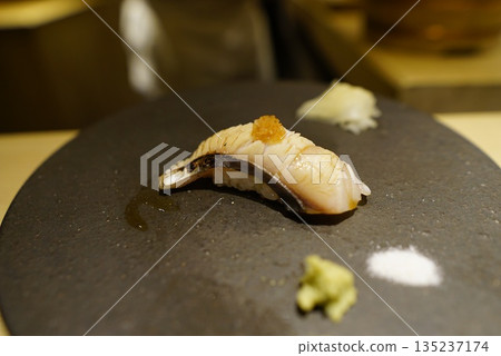 高級壽司餐廳的現代菜餚:炙烤鯖魚握壽司配佐料,盛於黑色石盤中。 高級壽司餐廳的現代菜餚:炙烤鯖魚握壽司配佐料,盛於黑色石盤中。 135237174