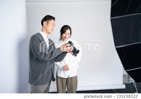 Man showing a photo to a female model in a studio Man showing a photo to a female model in a studio 135238322