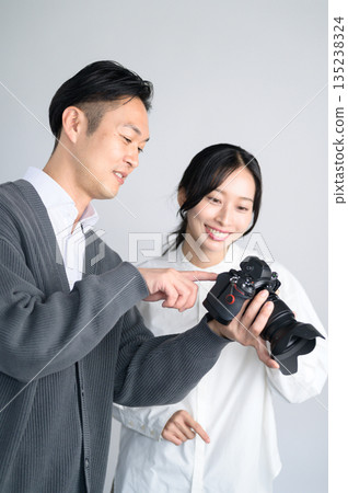 Man showing a photo to a female model in a studio Man showing a photo to a female model in a studio 135238324