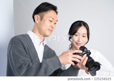 Man showing a photo to a female model in a studio Man showing a photo to a female model in a studio 135238325
