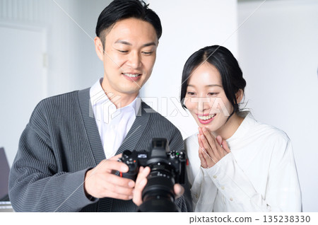 Man showing a photo to a female model in a studio Man showing a photo to a female model in a studio 135238330