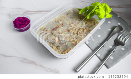Cold meat jelly. Congealed broth in a transparent bowl. Horseradish next to it. Cold meat jelly. Congealed broth in a transparent bowl. Horseradish next to it. 135238394