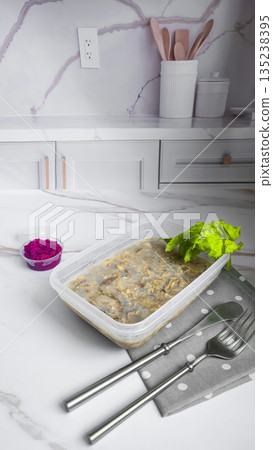 Cold meat jelly. Congealed broth in a transparent bowl. Horseradish next to it. 135238395
