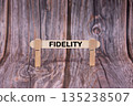 Fidelity symbol. A wooden stick clasped by clothespins set over a beautiful Brown Grunge Wooden Texture Background. Business and Fidelity concept with copy space 135238507