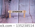 Leverage symbol. Single Wooden stick supported by Clothespins, beautiful Light Orange tone highlight Wooden Texture Background. Business and Leverage concept with copy space 135238514