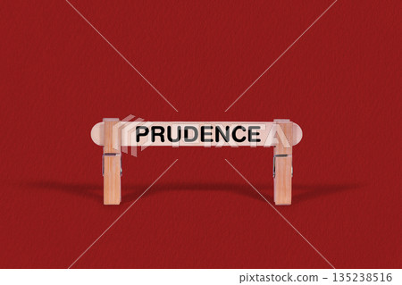 Prudence symbol. Wooden stick braced by Clothespins, beautiful Red Background. Business and Prudence concept with copy space Prudence symbol. Wooden stick braced by Clothespins, beautiful Red Background. Business and Prudence concept with copy space 135238516