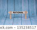 Rational symbol. Wooden stick clamped by Clothespins, vivid blue wooden backdrop. Business and Rational concept with copy space 135238517