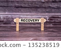 Recovery symbol. Wooden stick held by Clothespins, beautiful Realistic Grunge Wooden Background. Business and Recovery concept with copy space 135238519