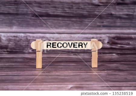 Recovery symbol. Wooden stick held by Clothespins, beautiful Realistic Grunge Wooden Background. Business and Recovery concept with copy space 135238519
