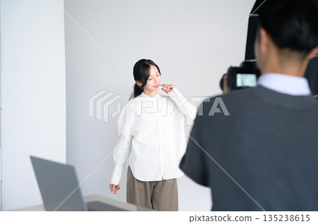 一位女模特兒和一位男攝影師正在指導 一位女模特兒和一位男攝影師正在指導 135238615