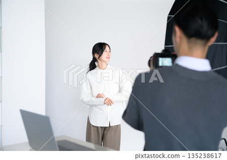 一位女模特兒和一位男攝影師正在指導 一位女模特兒和一位男攝影師正在指導 135238617