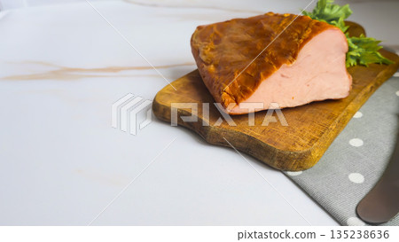 A piece of pork tenderloin on a wooden board. Smoked meat. Slices for a sandwich A piece of pork tenderloin on a wooden board. Smoked meat. Slices for a sandwich 135238636